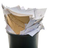 Ein überfüllter Papierkorb mit verschiedenen Dokumenten und Umschlägen, der die Notwendigkeit der digitalen Archivierung mit DocuWare als umweltfreundliche und effiziente Lösung verdeutlicht