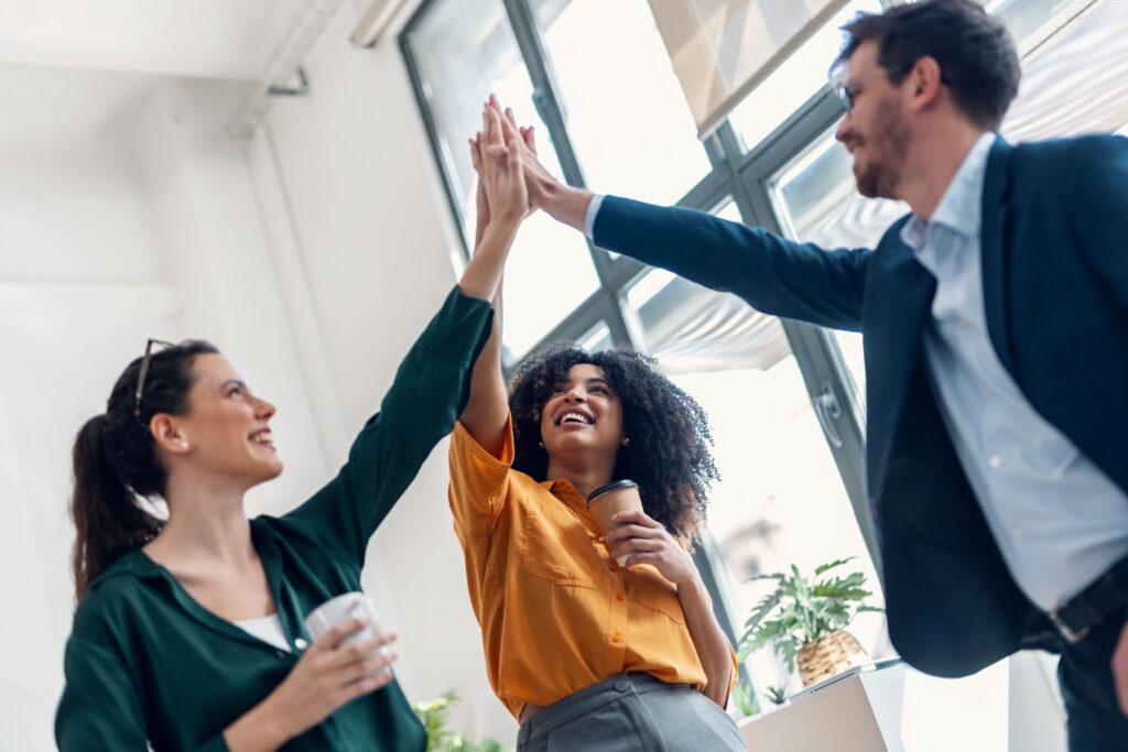 Drei Kollegen geben sich ein High-Five - Effiziente Organisation